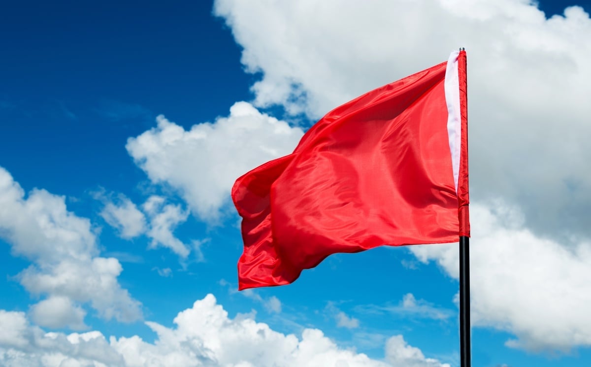 A red flag waving against a blue sky