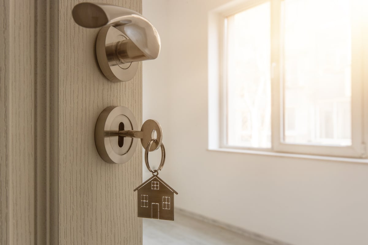 An open door to a property with a key and a home-shaped keychain in the lock