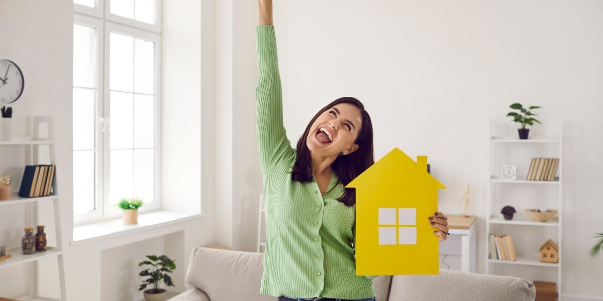 A happy tenant in her new home holding a picture of a house, tenant retention concept