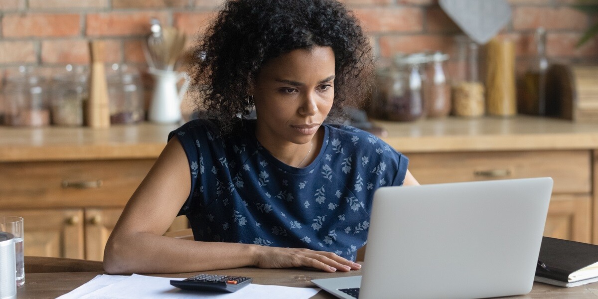 A woman working on tenant screening on her laptop at a table